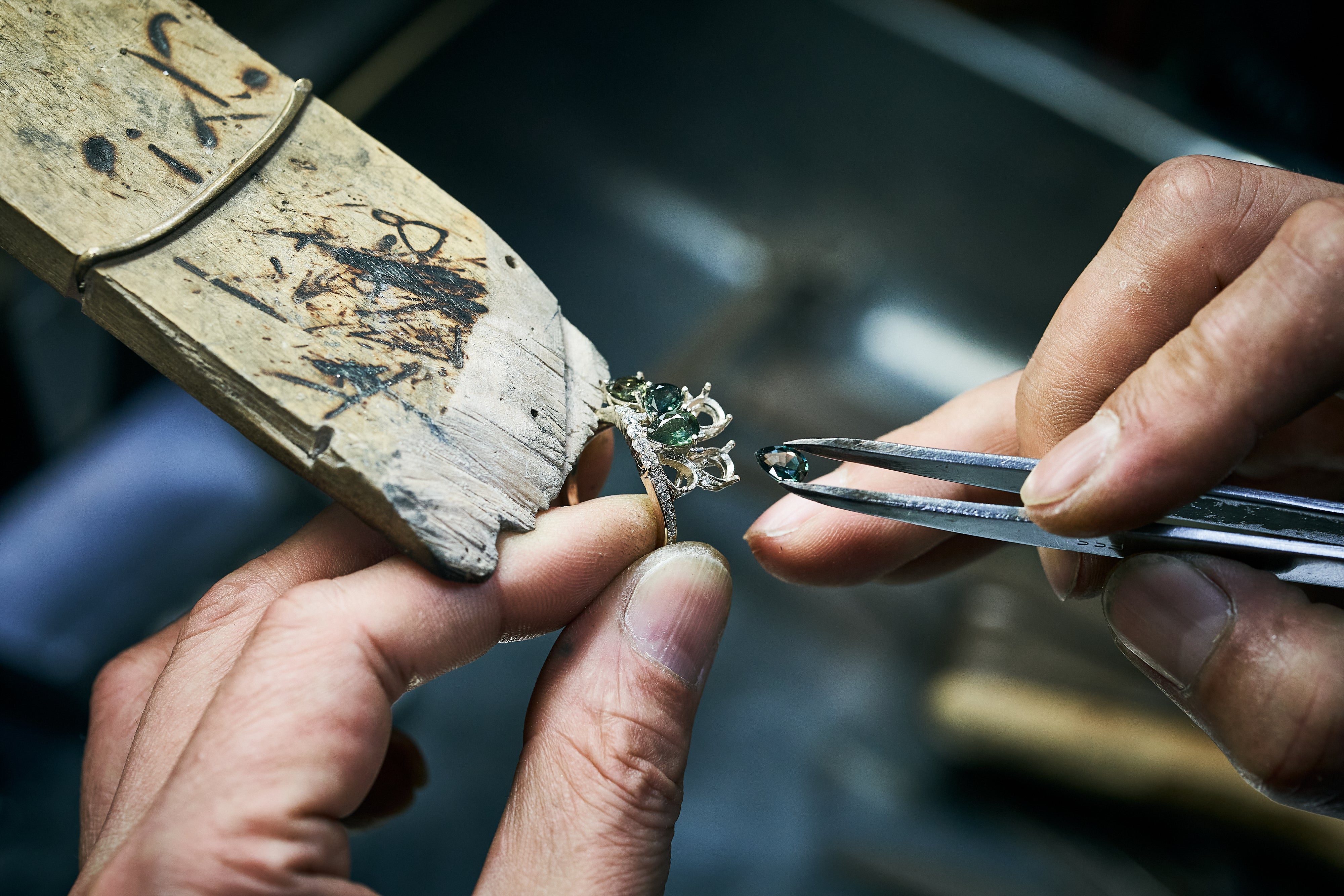 Tweezers insert green gemstone into ring frame